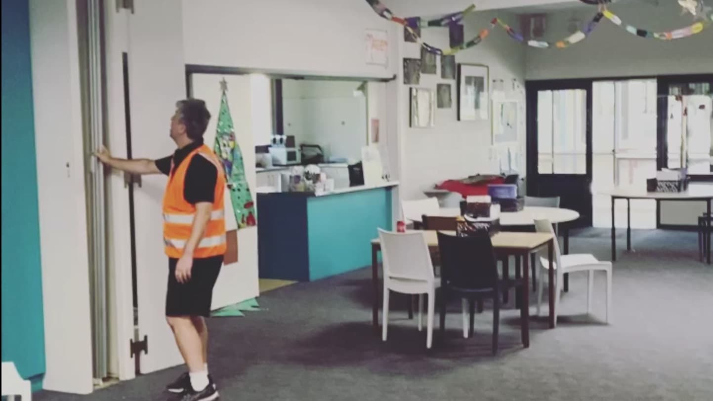 An installer folding a white accordion door back against the jamb of a community room