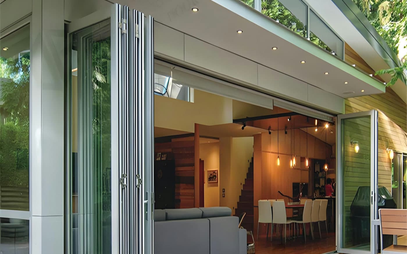 Glazed folding doors stacked back against the jamb, opening a living room onto a timber deck
